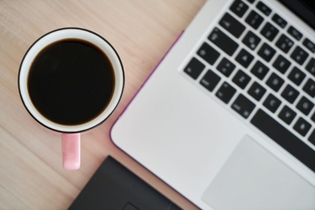 Coffee cup on desk next to open MacBook